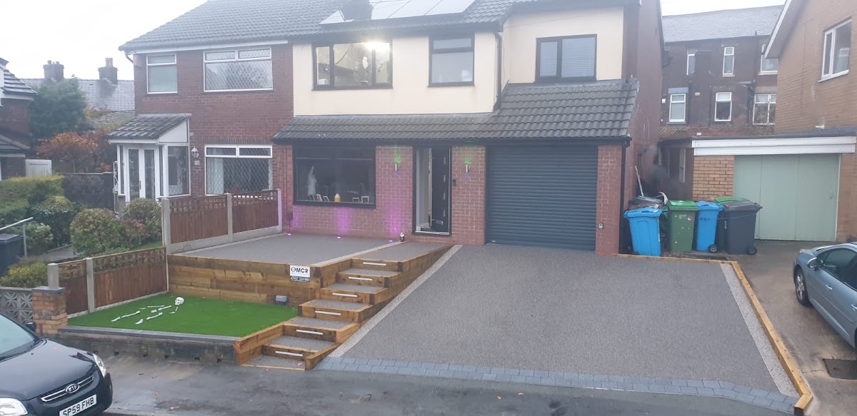 Silver-grey resin driveway with sleeper steps and artificial grass by MCR Resin Driveways